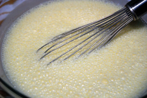 The milk is whisked with the vanilla, melted butter, and egg yolks. The egg whites will be incorporated later